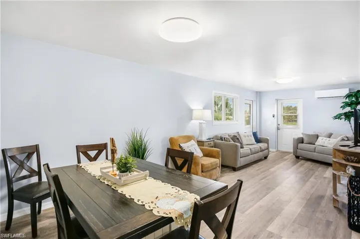 Dining room with light hardwood / wood-style flooring and a wall mounted AC