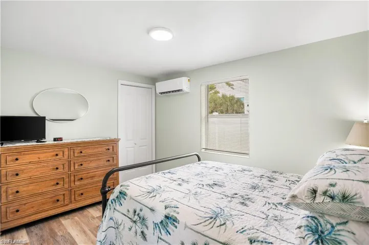 Bedroom featuring a wall mounted air conditioner, light hardwood / wood-style flooring, and a closet