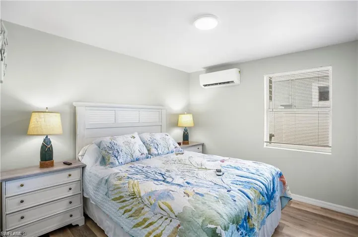 Bedroom with light hardwood / wood-style floors and a wall unit AC