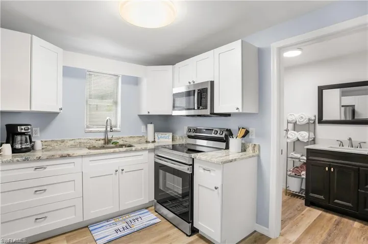 Kitchen featuring white cabinetry, sink, appliances with stainless steel finishes, and light hardwood / wood-style flooring