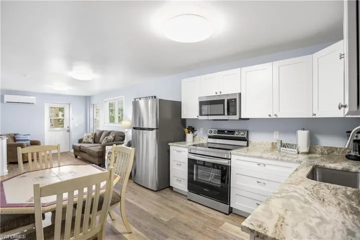 Kitchen featuring white cabinets, sink, an AC wall unit, and stainless steel appliances