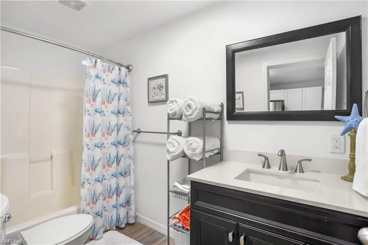 Full bathroom featuring hardwood / wood-style floors, vanity, shower / bath combo, and toilet