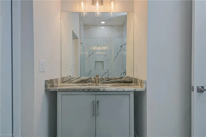 Full bath with vanity and a marble finish shower