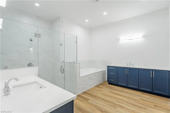 Bathroom featuring plus walk in shower, vanity, and hardwood / wood-style floors