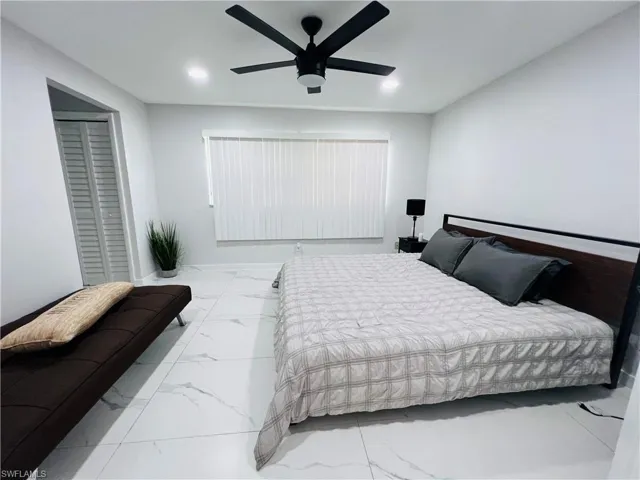 Recessed ceiling lighting, white tile flooring, ceiling fan, louvered closet doors, and window with vertical blinds
