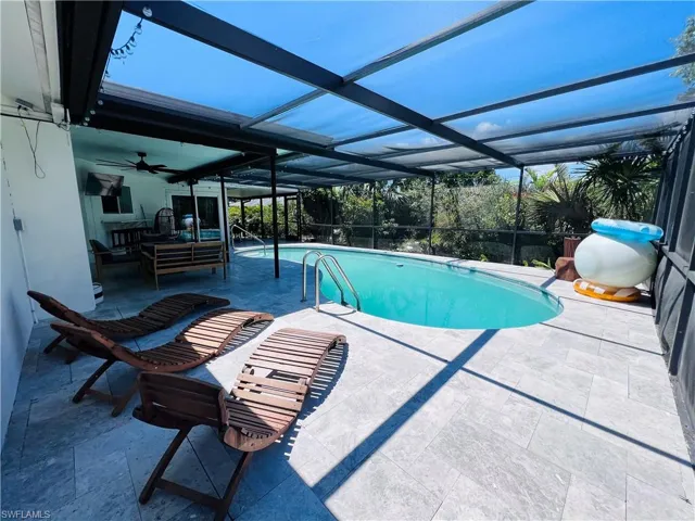 Screened-in outdoor pool featuring an oval shape and integrated steps
