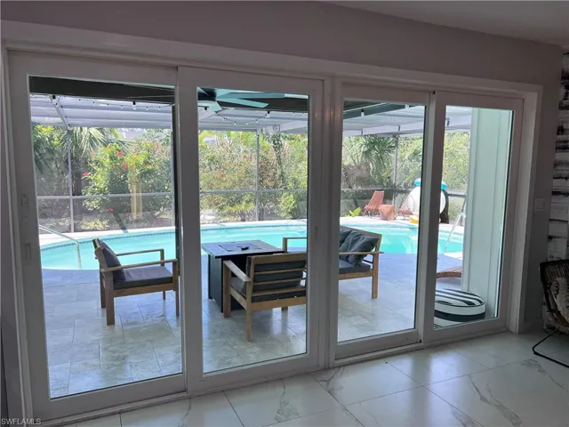 Expansive multi-panel sliding glass doors open to a screened lanai with a swimming pool