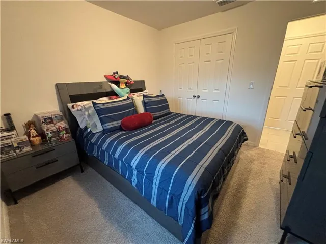 Bedroom featuring carpet flooring, visible vents, and a closet
