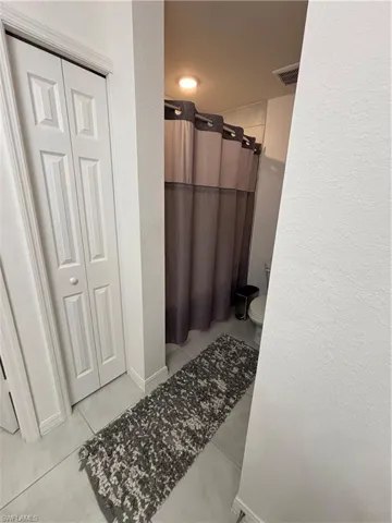Bathroom with visible vents, baseboards, toilet, a shower with curtain, and tile patterned floors