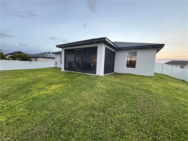 Rear view of property featuring a fenced backyard, screened in lanai
