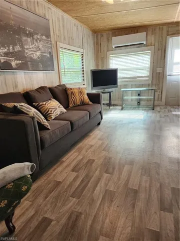 Living room featuring an AC wall unit, a healthy amount of sunlight, hardwood / wood-style flooring, and wood ceiling