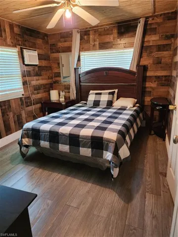 Bedroom with ceiling fan, hardwood / wood-style flooring, wood walls, and wooden ceiling