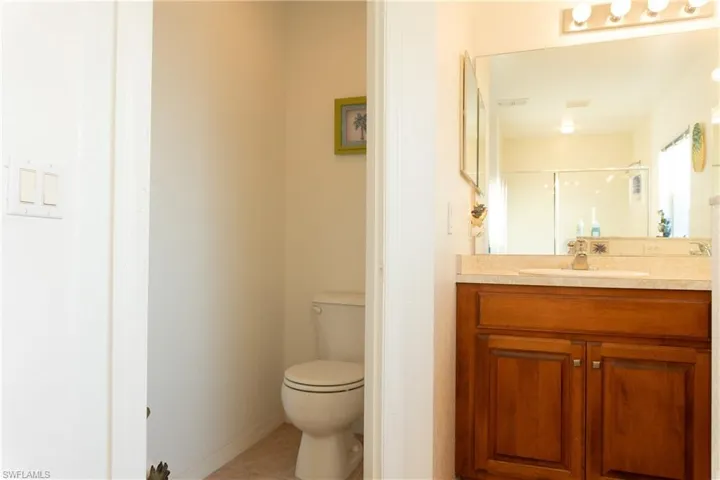 Bathroom with vanity, a shower with shower door, tile patterned floors, and toilet