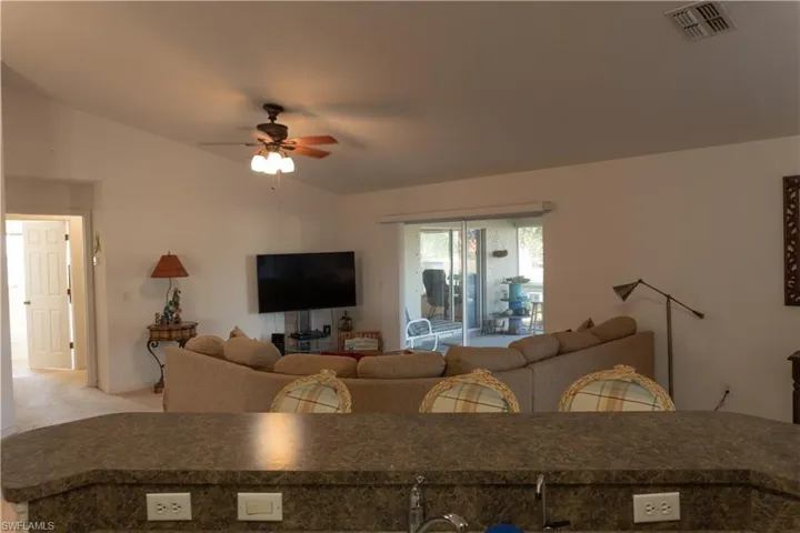 Living room featuring light colored carpet, ceiling fan, and vaulted ceiling