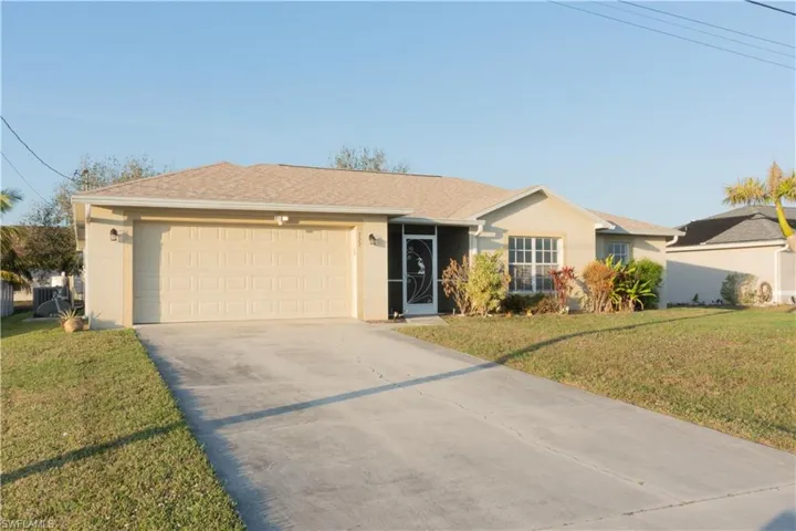 Ranch-style house with a garage, central air condition unit, and a front lawn