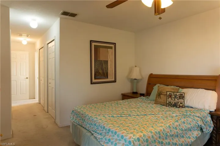 Carpeted bedroom featuring ceiling fan and a closet