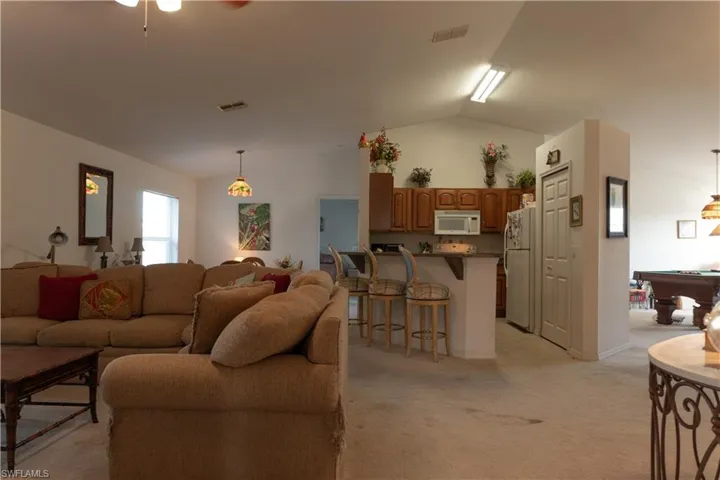 Carpeted living room with vaulted ceiling and billiards