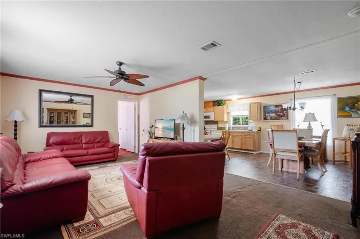 Tiled living room featuring ceiling fan and crown molding