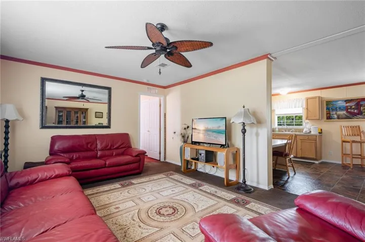 Tiled living room with ceiling fan, sink, and ornamental molding