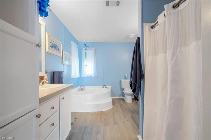 Bathroom featuring a bath, vanity, hardwood / wood-style floors, and toilet