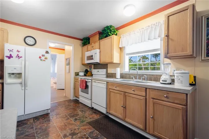 Kitchen featuring sink, dark wood-type flooring, white appliances, and ornamental molding