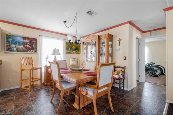 Dining space featuring dark tile patterned flooring, a notable chandelier, and ornamental molding