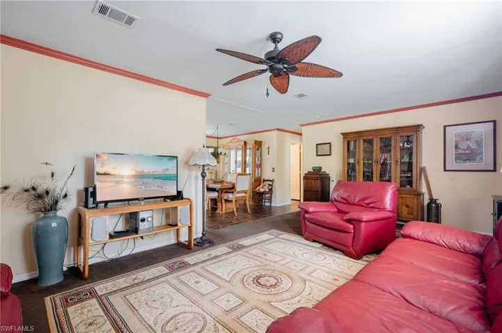 Carpeted living room with ceiling fan and ornamental molding
