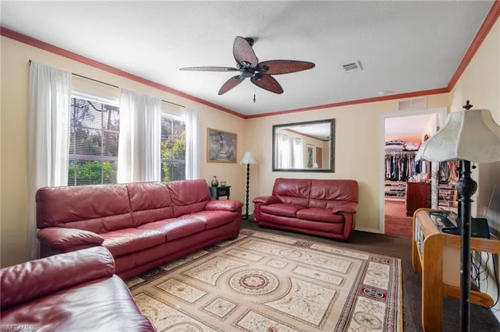 Carpeted living room featuring ceiling fan and ornamental molding