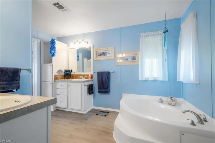 Bathroom with hardwood / wood-style floors, a tub, and dual vanity