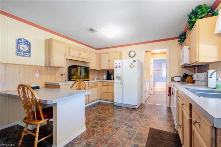 Kitchen featuring white appliances, ornamental molding, dark hardwood / wood-style flooring, and light brown cabinets
