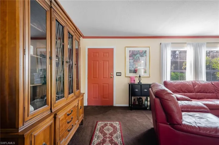 Living room with crown molding and dark carpet