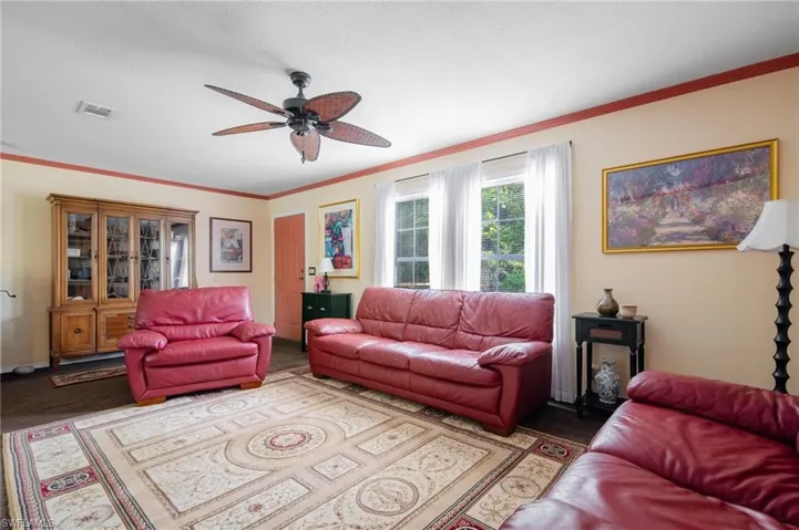 Living room featuring ceiling fan, crown molding, and wood-type flooring