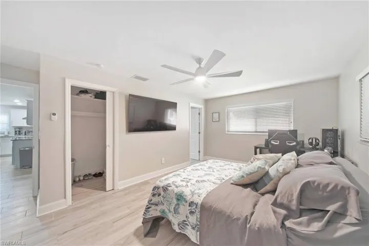 Bedroom featuring light wood-style flooring, a walk in closet, ceiling fan, and multiple windows