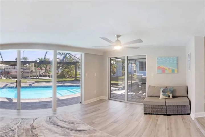 Living area with a sunroom, wood finished floors, plenty of natural light, and ceiling fan