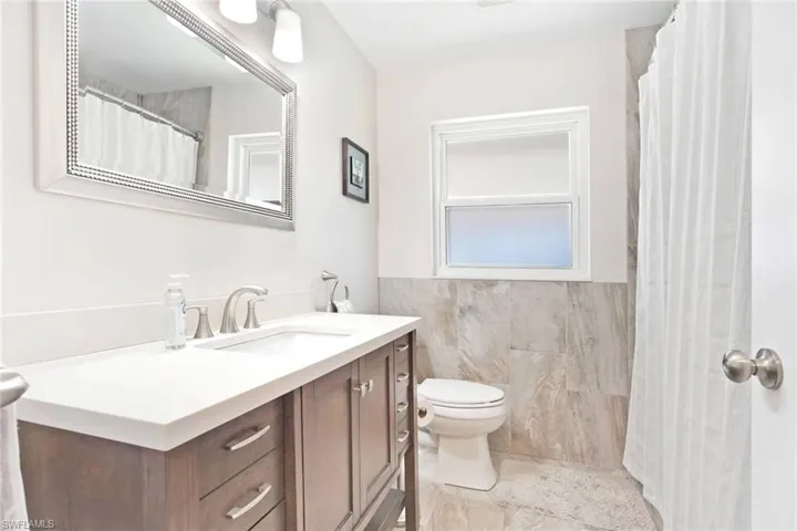 Bathroom featuring vanity, tile walls, a wainscoted wall, and a shower with curtain