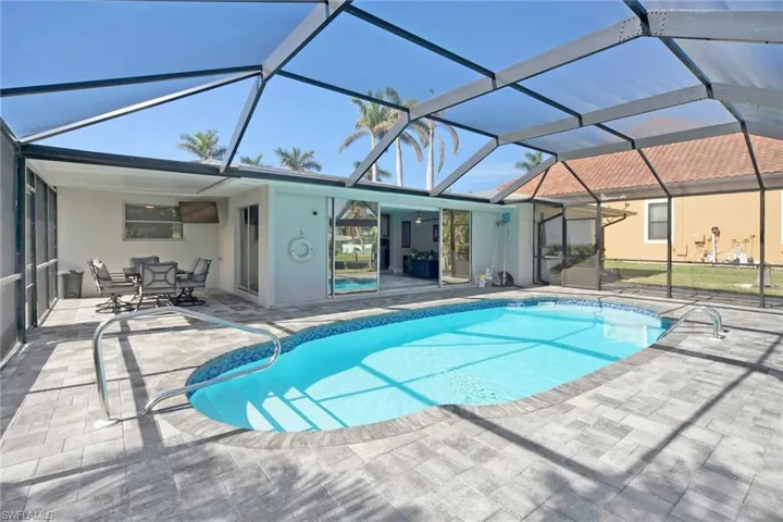 Swimming pool with a sunroom, a patio, and glass enclosure