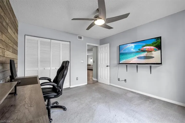 Carpeted office featuring a textured ceiling and ceiling fan