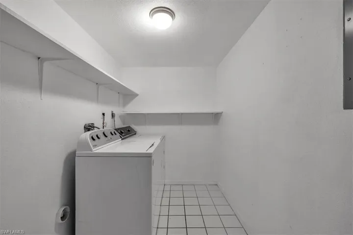 Laundry room with a textured ceiling, washing machine and clothes dryer, and light tile patterned flooring