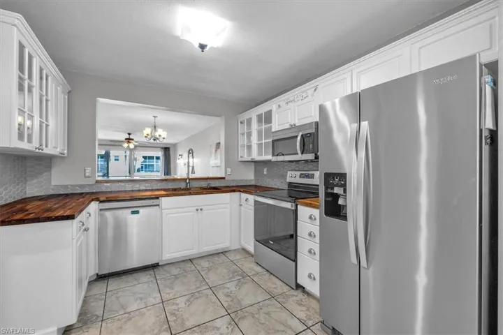 Kitchen featuring glass fronted cabinets, stainless steel appliances, and white cabinetry