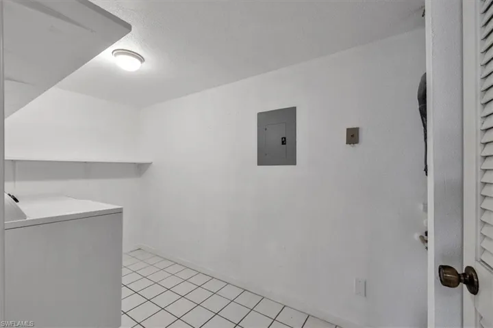 Laundry room featuring washer / dryer, electric panel, a textured ceiling, and light tile patterned floors