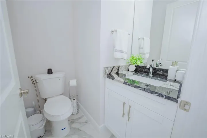 Half Bathroom with tile flooring, vanity, and toilet