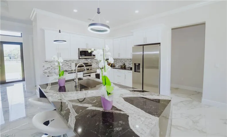 Kitchen featuring stainless steel appliances, light tile flooring, pendant lighting, light stone counters, and backsplash