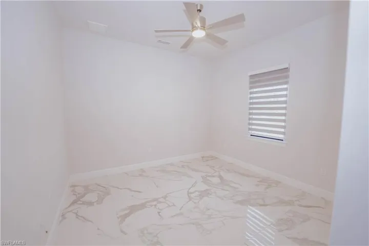 Tiled empty room featuring ceiling fan
