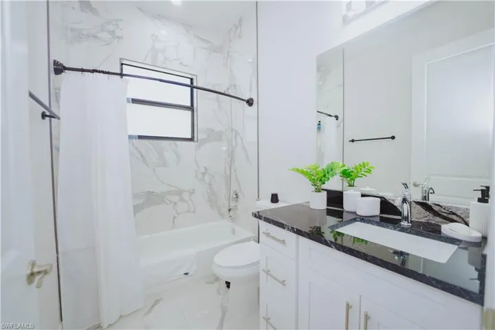 Full bathroom with tile flooring, shower / bath combination with curtain, toilet, and vanity