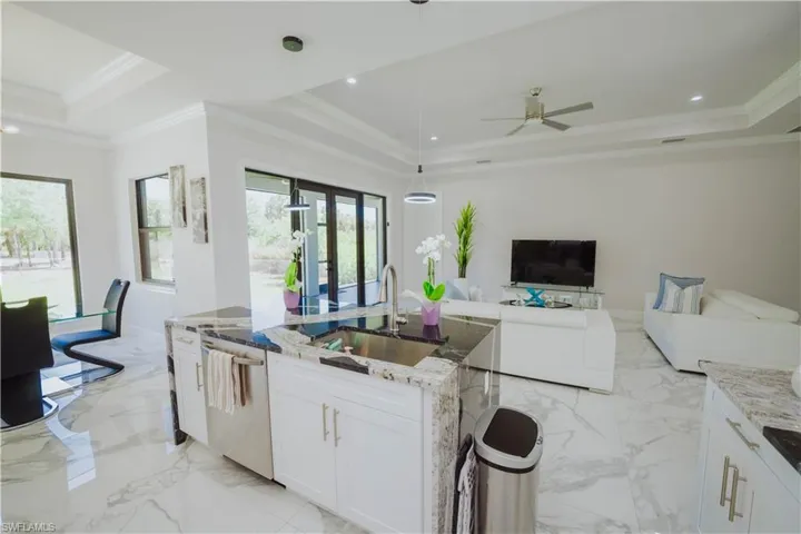 Kitchen with ceiling fan, a raised ceiling, decorative light fixtures, and light tile floors