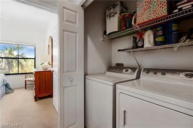 Laundry room featuring washer and clothes dryer and light colored carpet