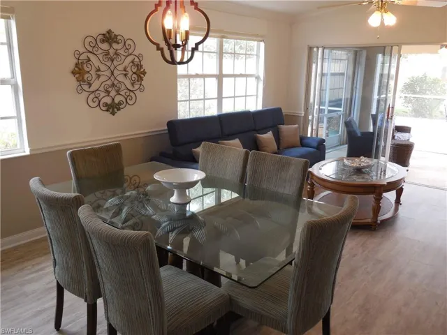 Dining room with light wood-style floors, ornamental molding, baseboards, and ceiling fan with notable chandelier