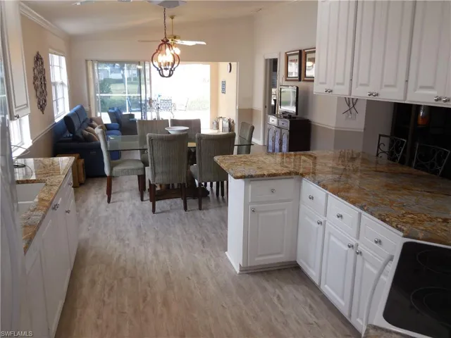 Kitchen featuring light wood-type flooring, electric stove, white cabinets, and light stone countertops