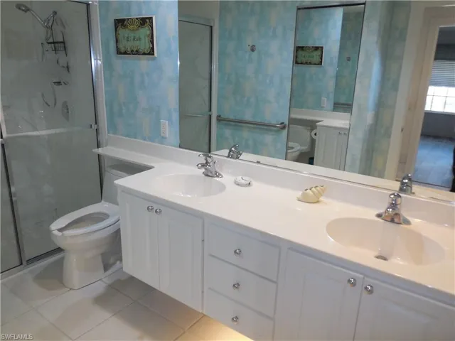 Bathroom with tile patterned flooring, a sink, a stall shower, and toilet