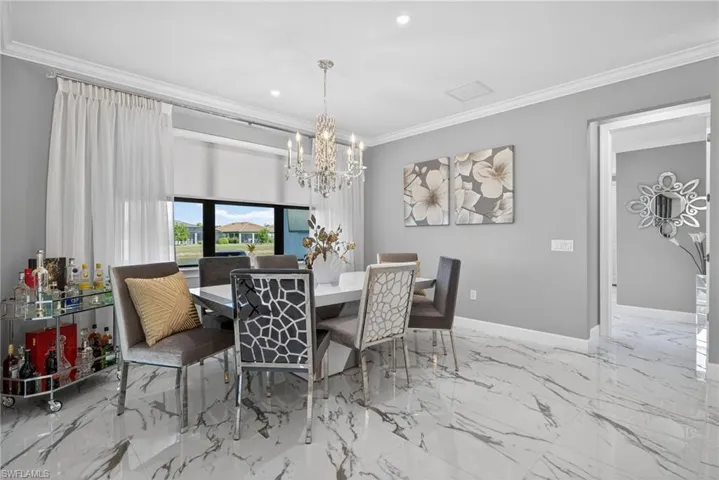 Dining space with crown molding, recessed lighting, a chandelier, and light marble finish floors